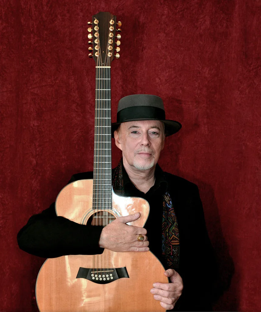 Michael Phillips mit seiner akustischen Taylor-Gitarre vor rotem Vorhang